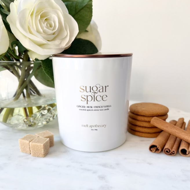 a 13oz white sugar spice candle with white roses, cinnamon sticks, a ginger snap cookie and sugar cubes